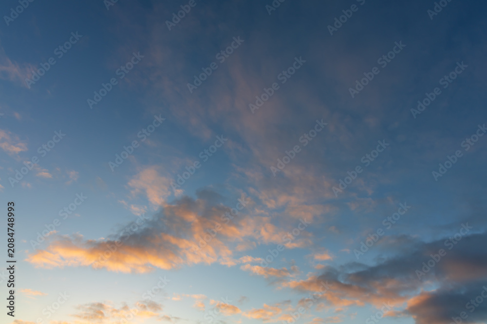 Fototapeta premium Clear Blue Sky with Wispy Orange Lit Clouds at Dawn Background