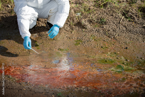 Fotografía Ecologist analyzing contaminated water source with flask and tools in protective