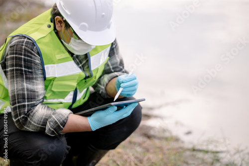 Ecologist examining water quality with a flask at a natural site conducting environmental research and analysis