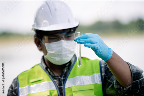 Ecologist analyzing water sample with flask in nature conservation area for environmental research and monitoring