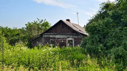 Foto An old abandoned wooden house with a slate roof and broken glass windows stands among the thickets of tall grass