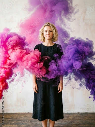 Woman standing in pink and purple smoke, creative portrait art.
