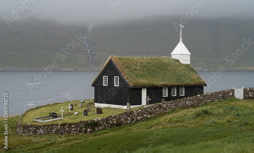 Traditional turf-roofed Kaldbak Church on the rocky coast of Streymoy island, Faroe Islands