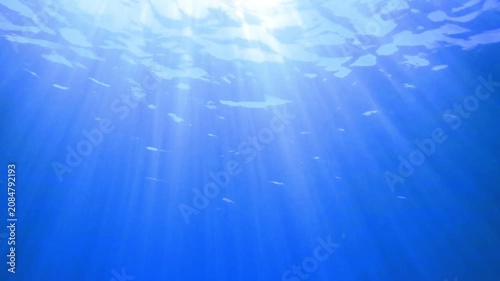 Dark blue ocean surface seen from underwater. Abstract waves underwater and rays of sunlight shining through, Sun light rays undersea deep, Underwater background with sea bottom, Mediterranean sea.