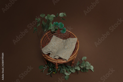 Woven Rattan Basket with Fabric and Eucalyptus Leaves on Brown Background