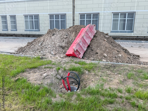 Fotografie Construction site with soil mound and red debris chute beside institutional building