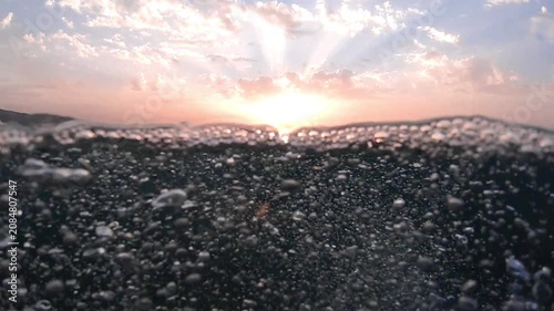 Underwater part and sunset skylight splitted by waterline, underwater bubbles. Beautiful clouds and bright sun over sea water, Real image very suitable for backgrounds in Mediterranean sea, undersea.