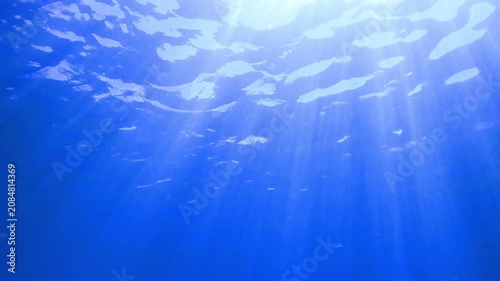 Light filtering down through blue water. Underwater sunlight in deep sea. Light viewed from blue abyss. Underwater sunlight shining deep with ripples on wave surface ocean ray, Under water Slow motion