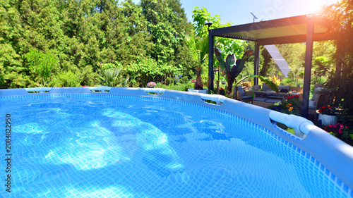Foto Outdoor swimming pool in a garden with lawn, plants and trees.