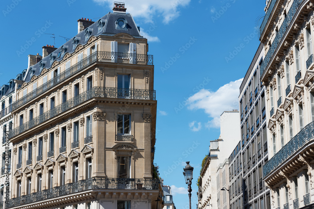 Obraz premium Magnificent Haussmann-style apartment buildings line the Avenue de l'Opera in the 2nd district of Paris, under a vivid blue sky.