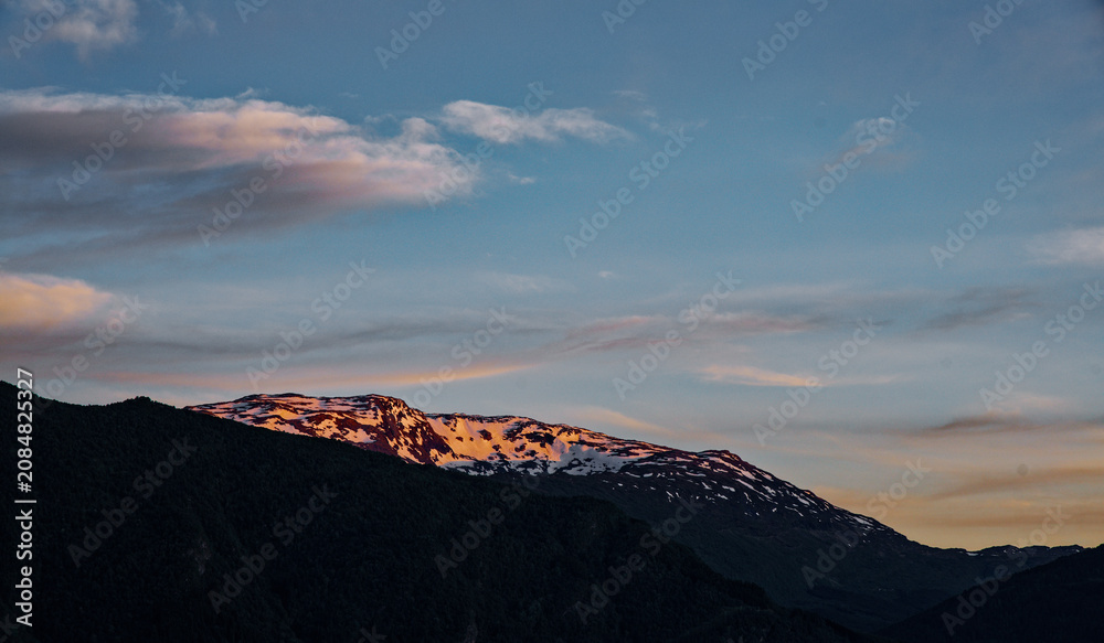 Obraz premium Golden Hour Glow on Snowy Mountain Peaks with Serene Sunset Sky