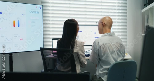 Asian staff engaged in a professional discussion. Planning and cooperation using a computer monitor for analysis and information sharing during a corporate workplace briefing.