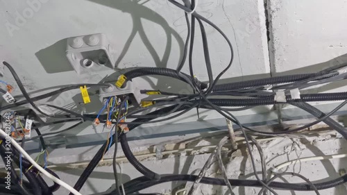 Unfinished electrical wiring with corrugated cable ducts and labeling on a concrete ceiling