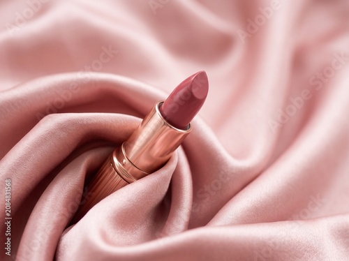 Pink lipstick on soft pink satin fabric close-up