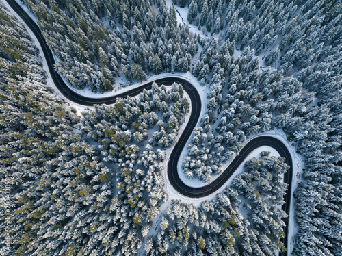 Aerial view of winding road, snow-covered trees, winter landscape, frozen forest