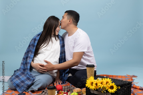 Happy romantic couple sitting close together on blanket enjoying picnic