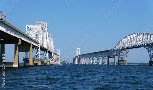 The view of Chesapeake Bay Bridge with distinct truss span across calm bay under a clear blue sky near Annapolis, Maryland, U.S.A