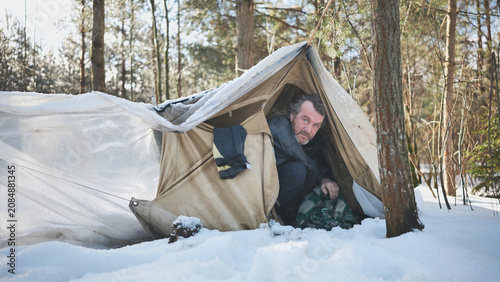 Foto Alcohol addicted homeless man seeks refuge from the cold in a makeshift tent in