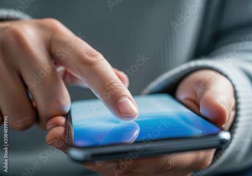 Close up shot of human hands using smartphone touchscreen with blue light reflection holding mobile device for browsing web or social media apps.