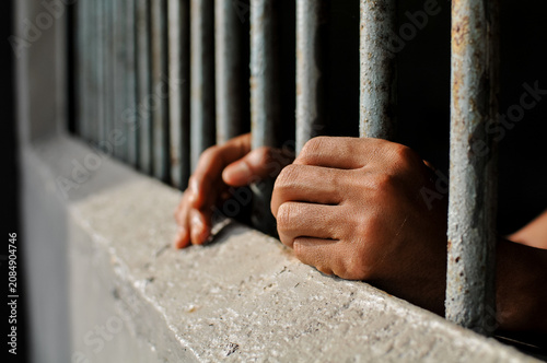 Tableau sur toile Close-up of a prisoner's hands gripping the iron bars of a jail cell