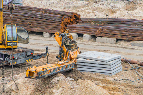 Fotografie Construction site featuring earth-moving machinery, concrete slabs, rebar, dirt,