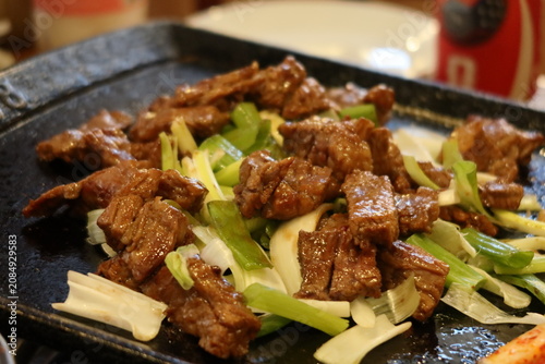 Traditional Korean barbecue featuring grilled marinated meats, fresh side dishes, and a tabletop grill. Warm, inviting dining scene showcasing authentic Korean cuisine and shared meals.
