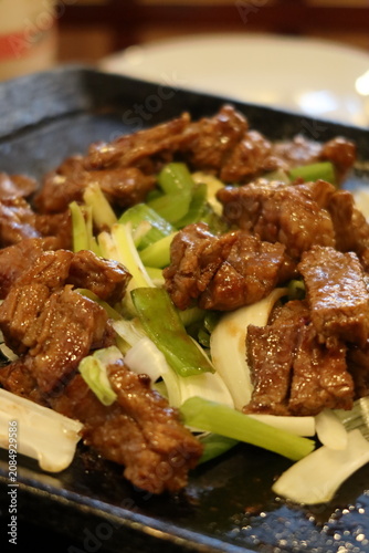 Traditional Korean barbecue featuring grilled marinated meats, fresh side dishes, and a tabletop grill. Warm, inviting dining scene showcasing authentic Korean cuisine and shared meals.