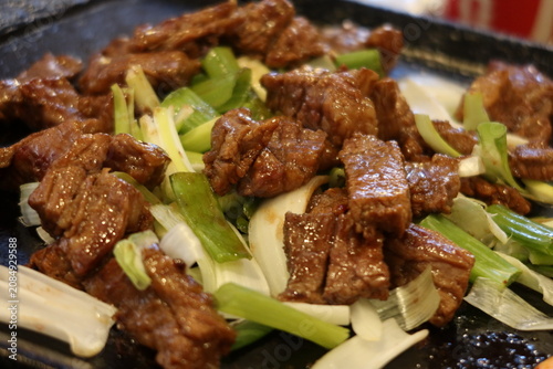Traditional Korean barbecue featuring grilled marinated meats, fresh side dishes, and a tabletop grill. Warm, inviting dining scene showcasing authentic Korean cuisine and shared meals.