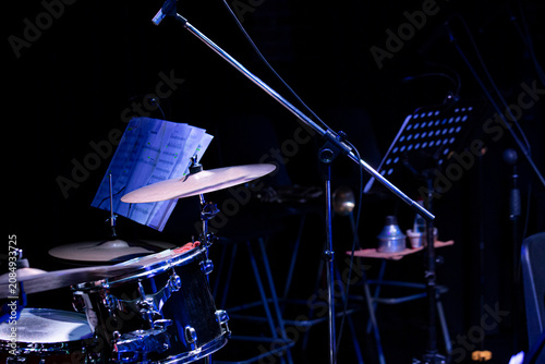 Sticker Close-up details of jazz instruments and musicians performing on stage under dramatic blue and purple concert lighting, featuring saxophone, piano, drumsticks and live music atmosphere