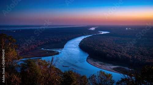 Aerial view of a winding river delta at blue hour with a dense forest canopy and glowing lights for travel and nature background