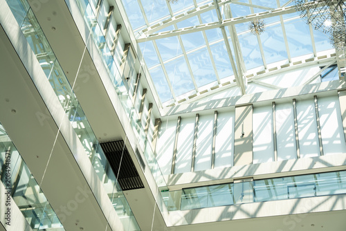 Interior view of a modern architectural glass atrium with abundant natural light. Corporate building design and contemporary workplace environment