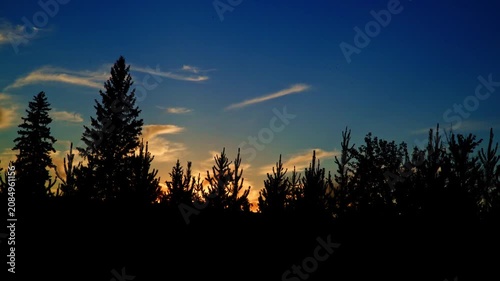 Distant views of spectacular colorful clouds illuminated by the last rays of the setting sun. Rich golden, orange, pink, and deep blue tones create a dramatic summer evening sky.
