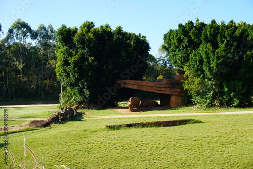 Rhinoceros resting in the shade of a wooden shelter on a sunny grassland