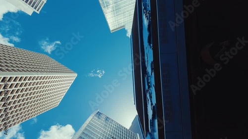 A panoramic view from below looking up at modern skyscrapers in Hong Kong's skyline, with buildings featuring glass and concrete structures