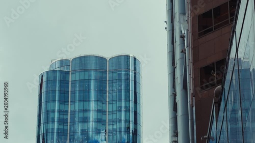 A bustling cityscape featuring towering skyscrapers and cylindrical towers in vibrant hues of cool blue and gray under an overcast sky