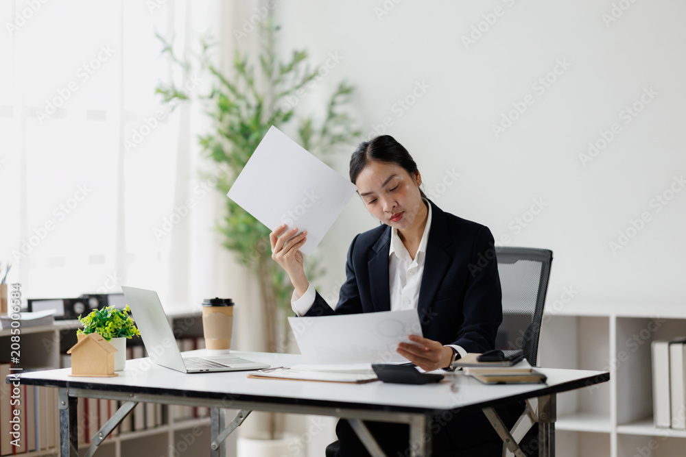 Fototapeta premium Asian businesswoman feeling overwhelmed by office paperwork