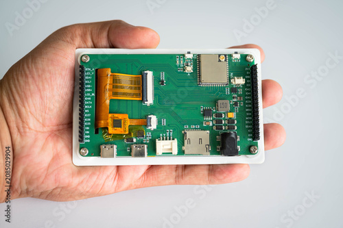 Fotografie Close-up of an embedded development board held in hand for hardware prototyping, featuring electronic circuitry for IoT, embedded systems, electronics engineering, smart devices