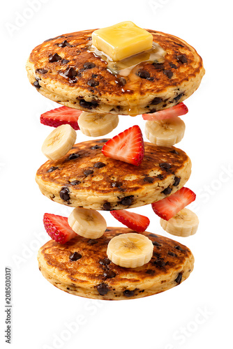 Stacked chocolate chip pancakes with butter syrup banana and strawberry slices for sweet breakfast dessert meal treat isolated on a transparent background