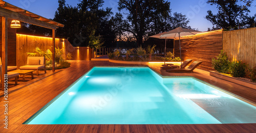 Obraz na płótnie Pool and lounge area with soft night lighting and lush garden