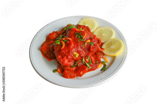 Spicy Red Fish Curry with Thick Tomato Gravy Garnished with Herbs and Lemon Slices on White Plate Isolated