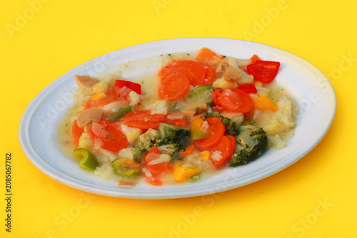 Stir Fried Mixed Vegetables with Broccoli and Carrots in White Sauce Served on Plate Over Bright Yellow Background