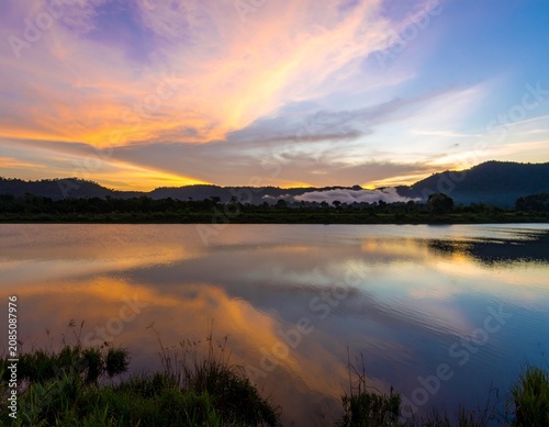 Background image of the reservoir. Beautiful sunrise or sunset sky over calm lake with reflection in surface water in the morning or evening. copy space. Lam Taphen Reservoir, Suphanburi.