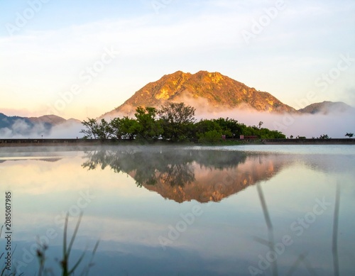 Background image of the reservoir. Beautiful sunrise or sunset sky over calm lake with reflection in surface water in the morning or evening. copy space. Lam Taphen Reservoir, Suphanburi.