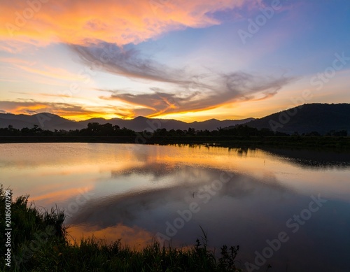 Background image of the reservoir. Beautiful sunrise or sunset sky over calm lake with reflection in surface water in the morning or evening. copy space. Lam Taphen Reservoir, Suphanburi.