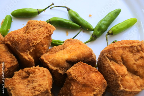 Fotografie Close up of Tahu Sumedang, Indonesian traditional deep fried tofu served with fresh green bird's eye chilies on a white plate