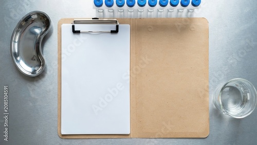 Empty clipboard with medical supplies arranged on a metallic lab table
