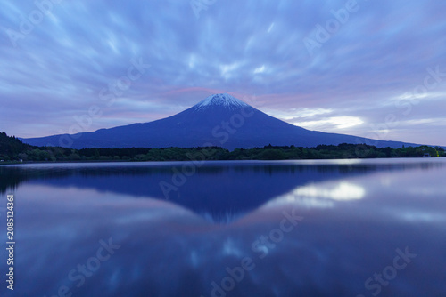 Mysterious blue hour landscape of Mount Fuji and its perfect reflection on Lake Tanuki before dawn in May, Shizuoka, Japan.