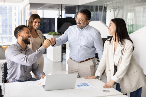 Mature Indian man exchanging fist bump with male colleague, celebrating joint success, encouraging or motivating each other before negotiations, expressing respect for work done. Team spirit and unity