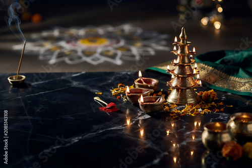 Diwali festival celebration with brass diya lamps on black marble. Traditional oil lamps and rangoli for Deepavali. Indian religious holiday background.