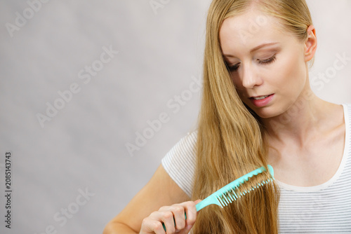 Fotografie Woman combing long healthy blonde hair
